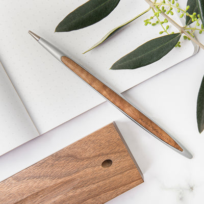 Pininfarina Segno "Cambiano Classic" Ethergraf Inkless pen with aluminum body and walnut wood inserts and base in a desk.