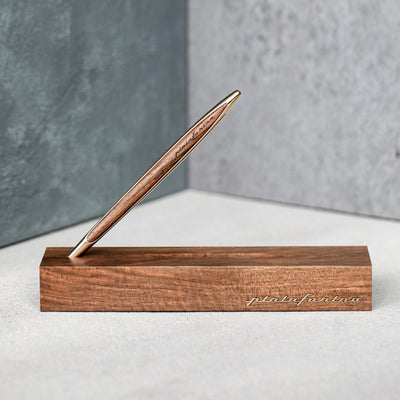Pininfarina Segno "Cambiano Luxury" Ethergraf Inkless pen with gold plated stem and walnut wood inserts standing in its walnut wood base.