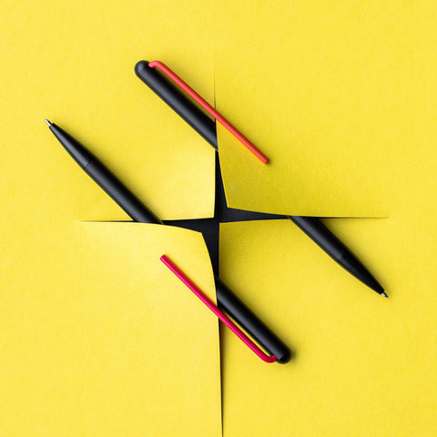 Two "Grafeex Ink" ballpoint pen with black aluminum body and red and magenta clip in a yellow background.
