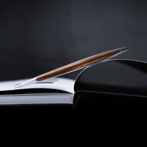 Pininfarina Segno "Cambiano Classic" Ethergraf Inkless pen with aluminum body and walnut wood inserts in a open notebook.
