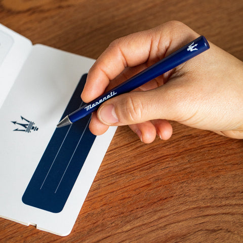 Hand holding the FO - Forever Made In Italy "Primina Maserati Edition" Ethergraf inkless pen in its blue version with the Maserati logo and trident.