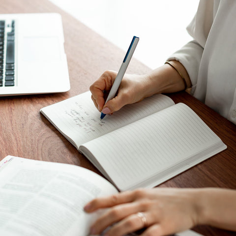 Woman writing in the Pininfarina Segno "Stone Paper Notebook" in its ruled version.