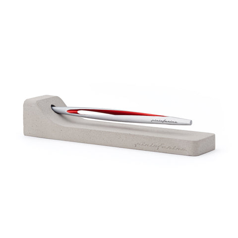 Pininfarina Segno "Aero" inkless pen with ethergraf tip with aluminum silver and red body in its concrete base in a white background.