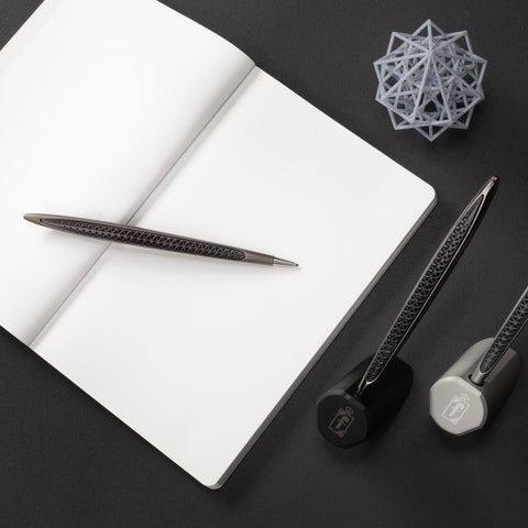 Pininfarina Cambiano Transitions Collection in both silver and black versions on their stands in a desk with a Notebook on the side