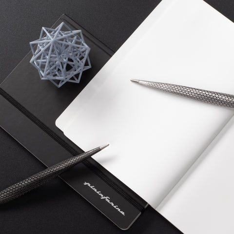 Pininfarina Speedform Transitions collections in its Titanium and silver versions on a desk with the Pininfarina Notebook Stone Paper