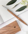 Pininfarina Segno "Cambiano Classic" Ethergraf Inkless pen with aluminum body and walnut wood inserts and base in a desk.
