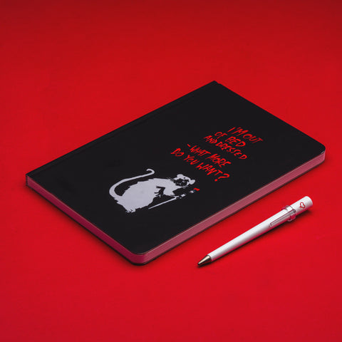 Pininfarina Segno special edition "Banksy's Graffiti Notebook + Primina Pen" in its version "Out of Bed Rat." with a white rat holding a brush in black background, next to a red text: "I'm out of bed and dressed" - What more do you want?". White "Primina" inkless ethergraf pen with a little heart graffiti.