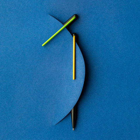 Two "Grafeex Ink" ballpoint pen with black aluminum body and green and yellow clip in a blue background.