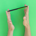 Hand holding a "Grafeex pencil" with black aluminum body and green clip in a green background.