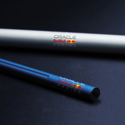 Close up of the Pininfarina Segno "SMART Oracle Red Bull Racing Edition" pencil with grafeex tip and blue painted aluminum body with the Oracle Red Bull Racing logo, next to its packaging aluminum tube.