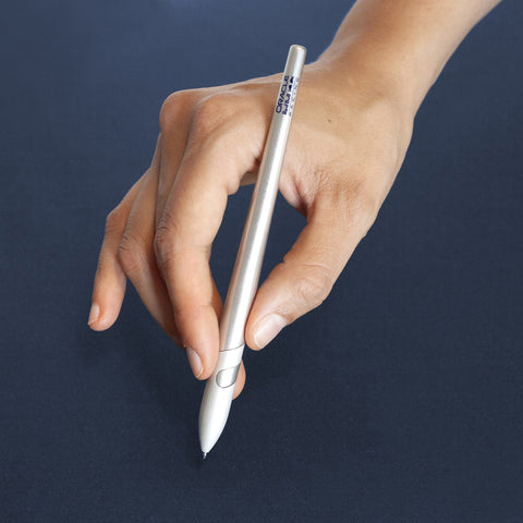 Hand holding the "Sostanza® Silver Ink Oracle Red Bull Racing" special edition ballpoint pen with aluminum body in a blue background.