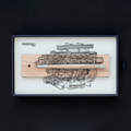 Pininfarina Segno "Cambiano Engine Maserati Special Edition" luxury ethergraf inkless pen with aluminum body and cedar wood inserts standing in its cedar wood base with a drawing of an engine inside of its packaging.