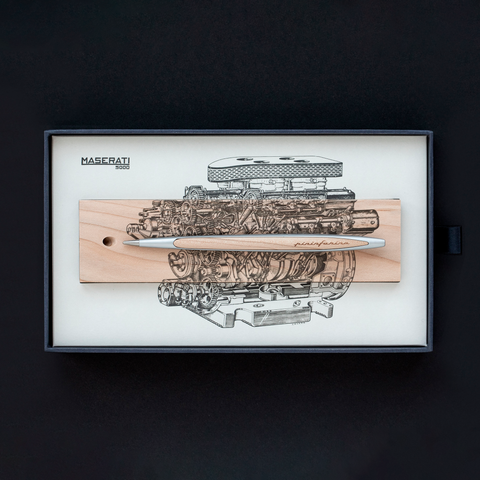 Pininfarina Segno "Cambiano Engine Maserati Special Edition" luxury ethergraf inkless pen with aluminum body and cedar wood inserts standing in its cedar wood base with a drawing of an engine inside of its packaging.