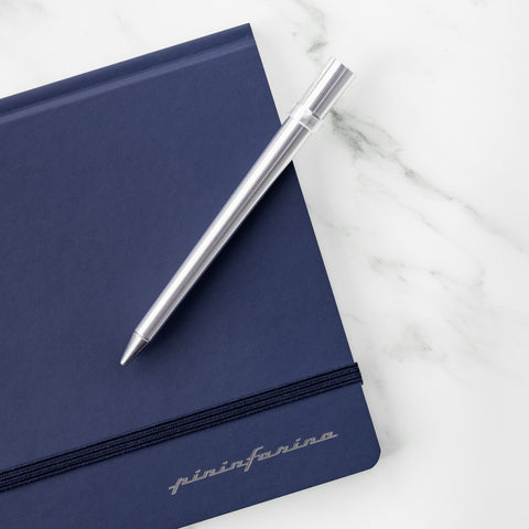 FO - Forever Made In Italy "Primina" Ethergraf inkless pen in silver above a Pininfarina stone paper notebook.
