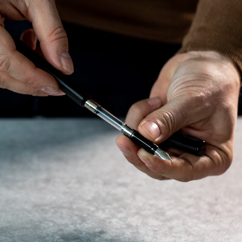 Man disassembling the Pininfarina Segno "PF ONE Fountain Pen" in its black version to show the refill.