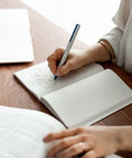 Woman writing in the Pininfarina Segno "Stone Paper Notebook" in its ruled version.