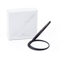 Pininfarina Segno "Space" ethergraf inkless pen with magnesium body in its black version standing in its ellipsoidal aluminum desk base next to its packaging box.