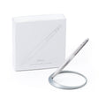 Pininfarina Segno "Space" ethergraf inkless pen with magnesium body in its pure gray version standing in its ellipsoidal aluminum desk base next to its packaging box.