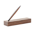 Pininfarina Segno "Cambiano Classic" Ethergraf Inkless pen with glossy black aluminum body and walnut wood inserts standing in its base in a white background.