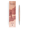Pininfarina Segno "Cambiano Paradiso 700th edition" ballpoint pen with aluminum body and cedar wood inserts next to its with an illustration of a fragment of the Divine Comedy of Dante Alighieri with a man walking in clouds.