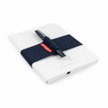 Pininfarina blue elastic band with the Pininfarina PF TWO in its dark blue version on its pen holder, while is covering the Pininfarina Notebook Stone Paper in its soft cover white version