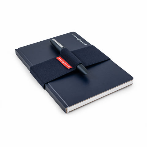 Pininfarina blue elastic band with the Pininfarina PF TWO in its dark blue version on its pen holder, while is covering the Pininfarina Notebook Stone Paper in its soft cover blue version