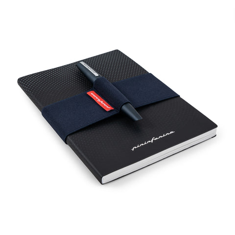 Pininfarina blue elastic band with the Pininfarina PF TWO in its dark blue version on its pen holder, while is covering the Pininfarina Notebook Stone Paper in its soft cover black version